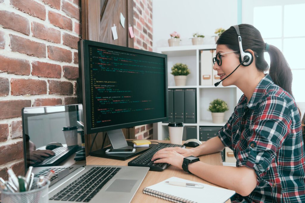 A woman on a computer with a headset helping a customer.